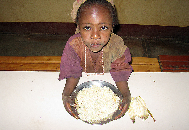 Girl in Africa hold bowl of food.